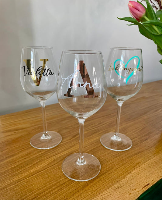 Personalisierbare Weingläser auf dem Holztisch mit Blumen im Hintergrund