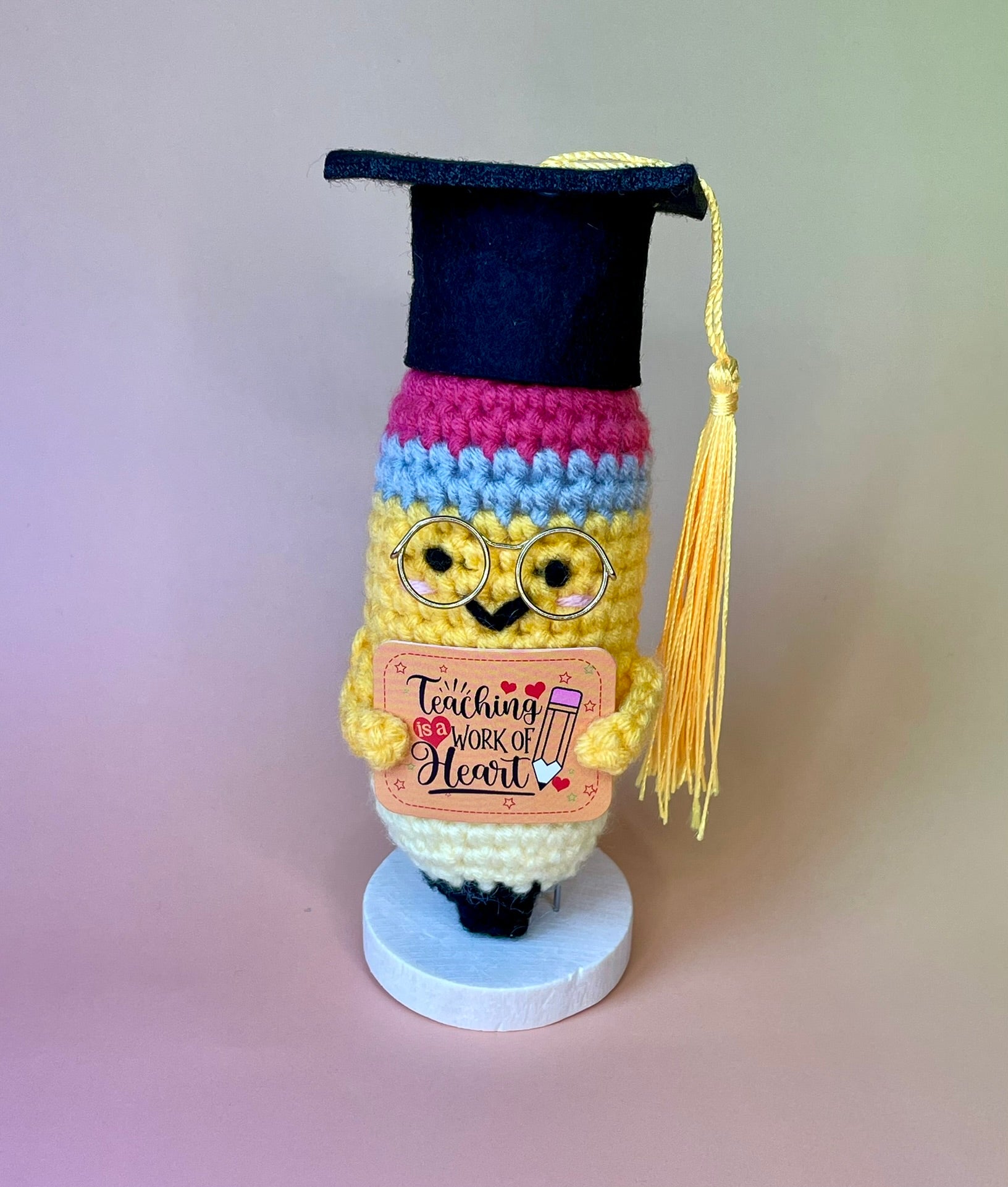 Gehäkelte Bleistift-Figur mit Diplomhut – seitliche Ansicht auf Holzsockel, personalisiertes Geschenk für Lehramt
