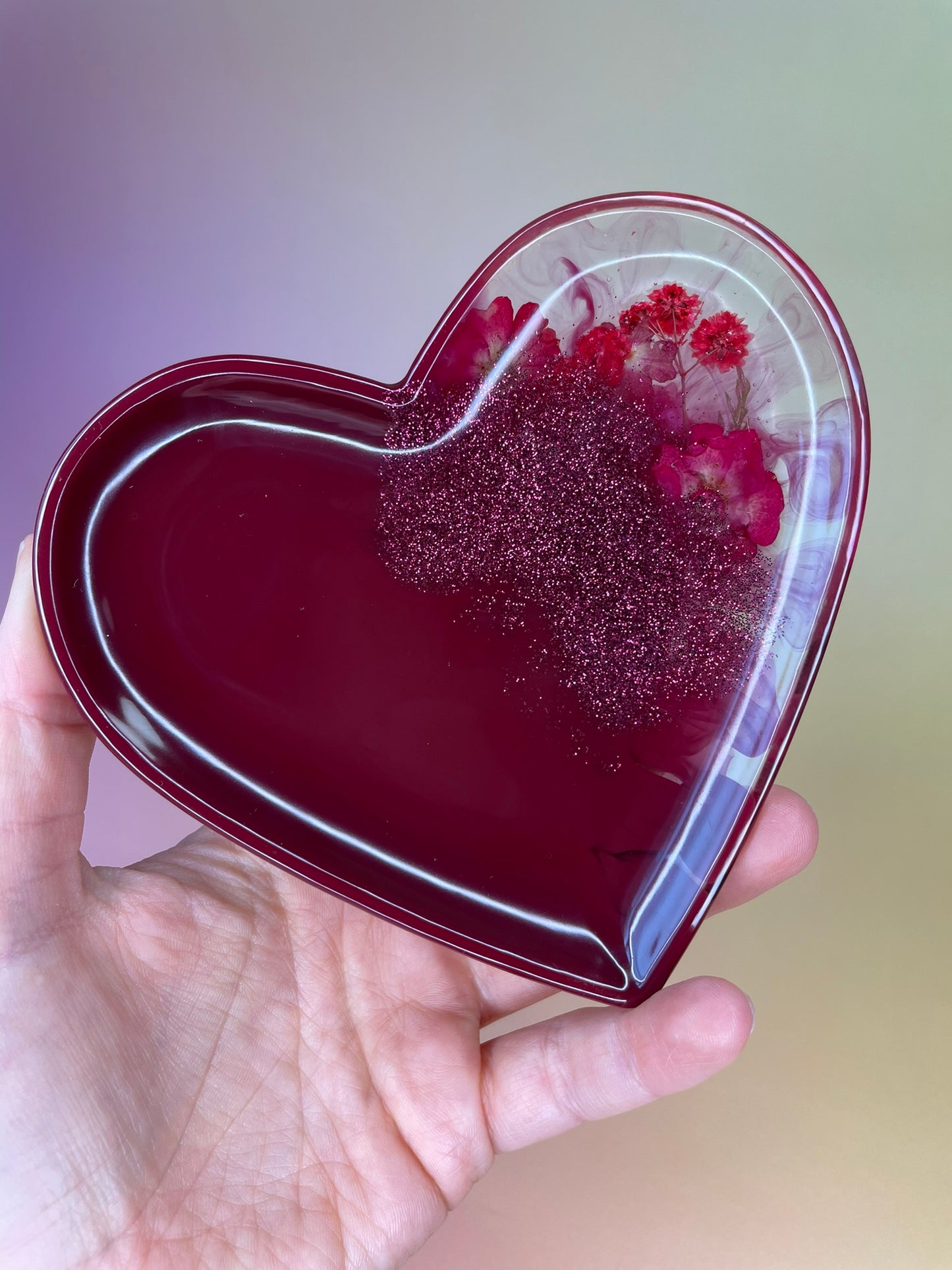 Herzförmiges Schälchen aus Epoxidharz mit echten Blumen in Dunkelrot - in der Hand gehalten 
