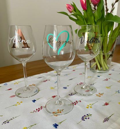 personalisierte Weingläser auf dem Tisch - daneben Tulpen in einer Vase als Dekoration 
