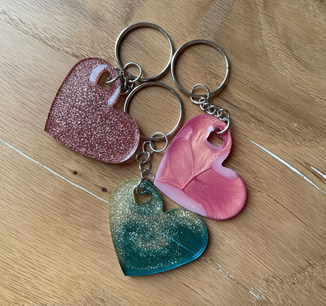Drei Stück herzförmige Epoxidharz Schlüsselanhänger - in Rosa Glitzer, Rosa soft Glam, und Blau-Champage Farben.