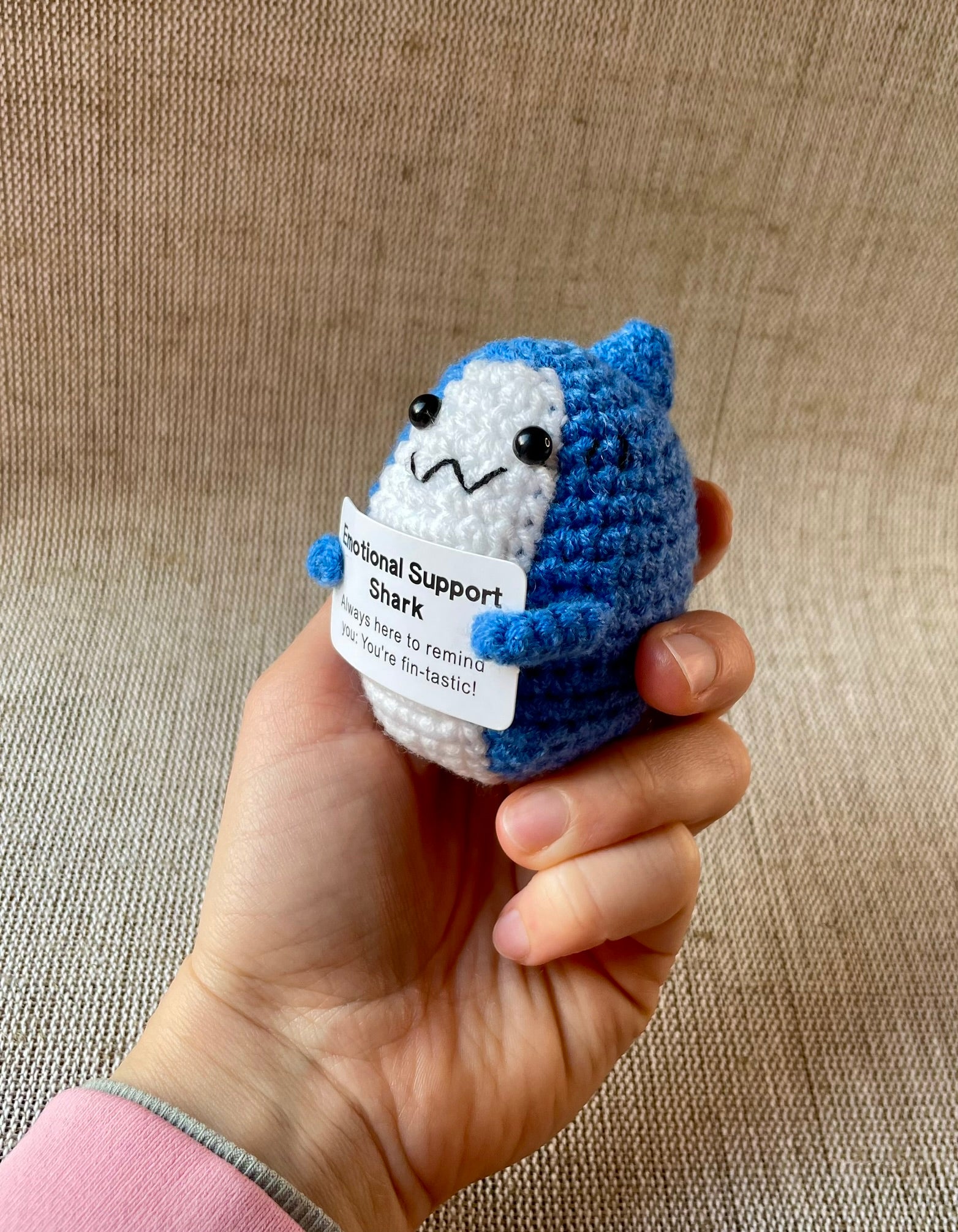 Gehäkelter Amigurumi Hai mit positiver Botschaft in der Hand gehalten.